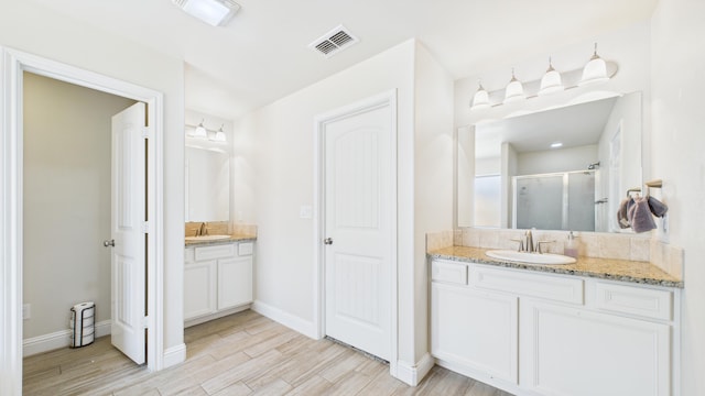 full bath featuring a stall shower, baseboards, wood finished floors, and vanity