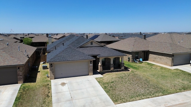 view of front of house featuring a front yard, a garage, a shingled roof, brick siding, and concrete driveway