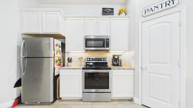 kitchen featuring white cabinets, tasteful backsplash, appliances with stainless steel finishes, and light stone counters