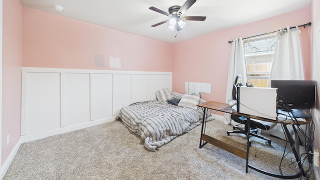 bedroom featuring a decorative wall, a wainscoted wall, ceiling fan, and carpet