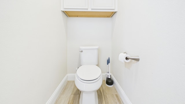 bathroom with wood finished floors, toilet, and baseboards