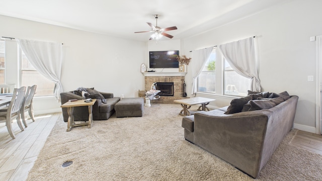 living room with a fireplace, a ceiling fan, wood finished floors, and baseboards