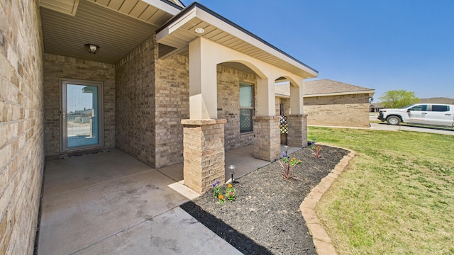 doorway to property featuring a lawn and brick siding