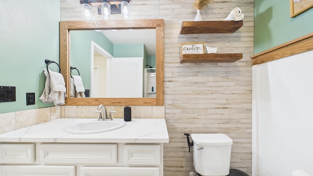 bathroom featuring wood walls, an inviting chandelier, toilet, and vanity