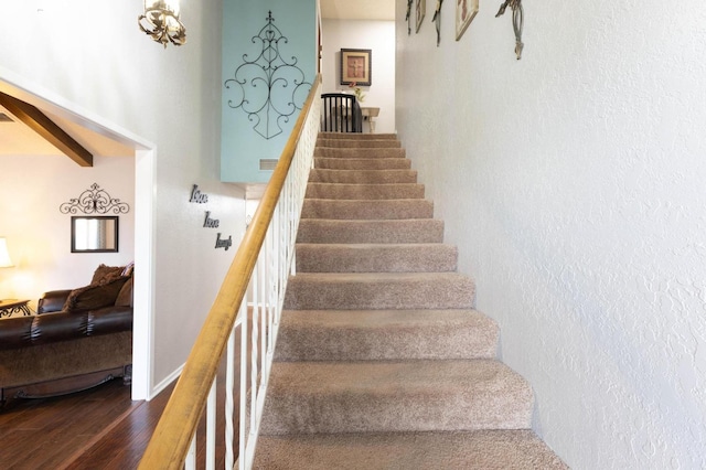 staircase featuring hardwood / wood-style flooring and beamed ceiling