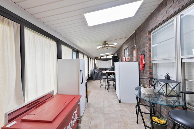 sunroom with tile patterned floors and vaulted ceiling with skylight
