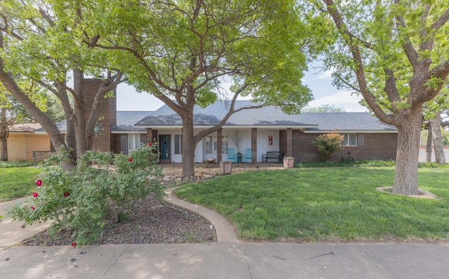 ranch-style house with a front lawn, roof with shingles, and brick siding