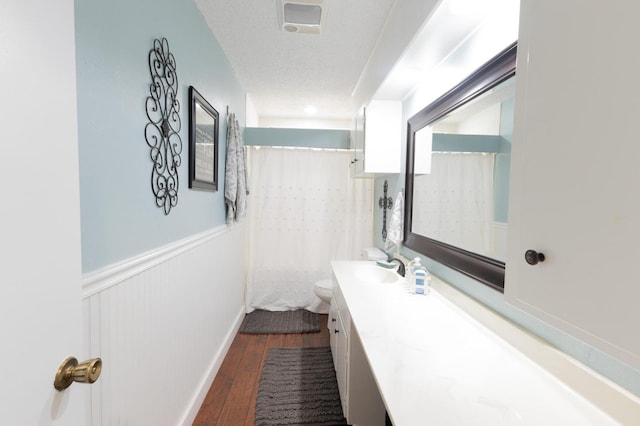 bathroom featuring wood-type flooring, vanity, toilet, a textured ceiling, and a shower with curtain