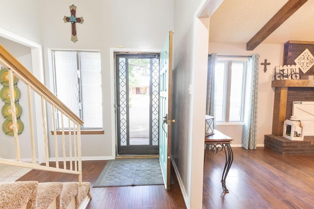 foyer featuring dark hardwood / wood-style flooring, a textured ceiling, and beamed ceiling