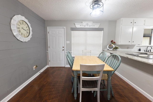 dining area with sink, a textured ceiling, and dark hardwood / wood-style flooring