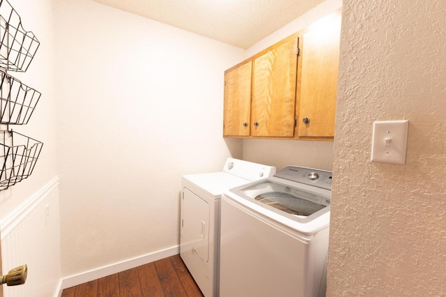 washroom featuring dark hardwood / wood-style flooring, washer and clothes dryer, and cabinets