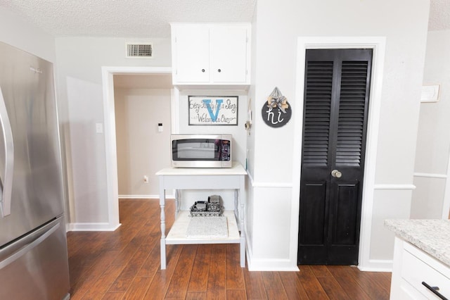 kitchen featuring white cabinetry, stainless steel appliances, dark hardwood / wood-style flooring, and a textured ceiling