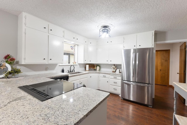 kitchen with sink, stainless steel fridge, white cabinetry, dark hardwood / wood-style floors, and light stone counters