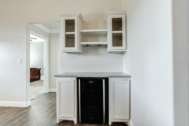 kitchen featuring white cabinetry, dark hardwood / wood-style floors, beverage cooler, and light stone counters