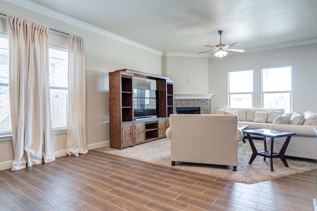 living room with a brick fireplace, ornamental molding, and ceiling fan