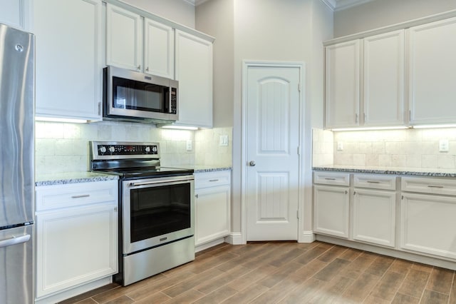 kitchen with white cabinetry, tasteful backsplash, appliances with stainless steel finishes, and light stone counters