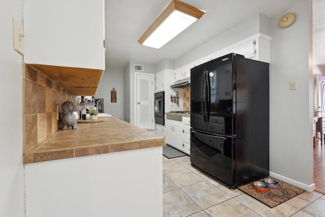 kitchen with white cabinets, light tile patterned floors, decorative backsplash, and black appliances