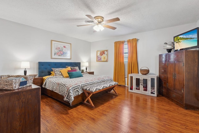 bedroom with ceiling fan, hardwood / wood-style floors, and a textured ceiling