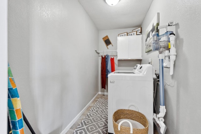 washroom featuring cabinets, washing machine and dryer, and a textured ceiling