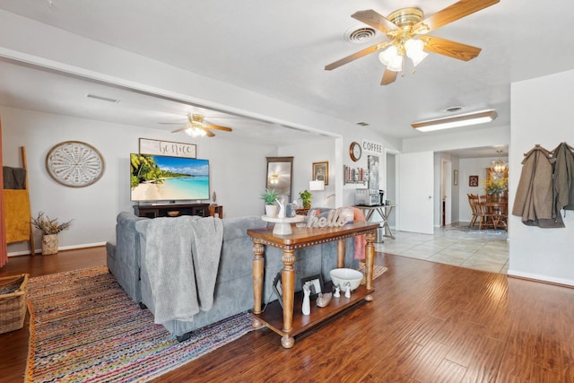 living room with ceiling fan with notable chandelier and light hardwood / wood-style flooring