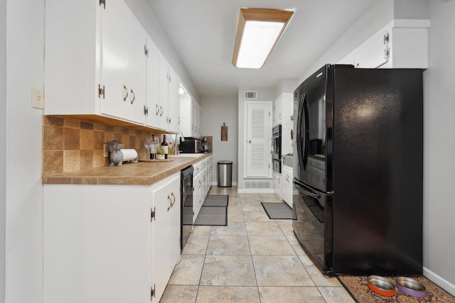 kitchen with white cabinetry, backsplash, light tile patterned floors, and black appliances