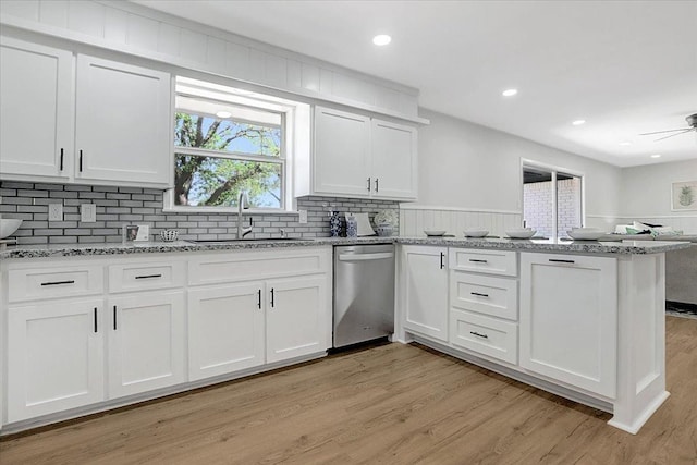 kitchen with white cabinetry, dishwasher, sink, kitchen peninsula, and light hardwood / wood-style flooring