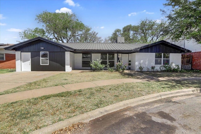 view of front of home featuring metal roof, brick siding, and a front lawn