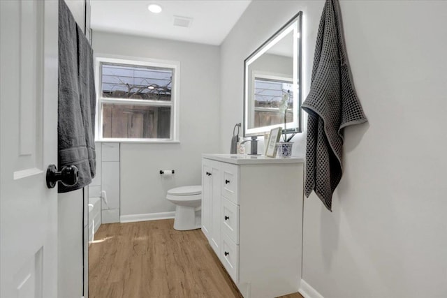 bathroom with visible vents, toilet, wood finished floors, baseboards, and vanity