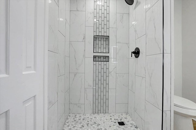 bathroom featuring toilet and a tile shower