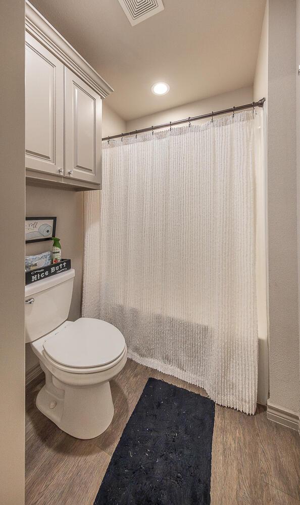 10323 Ave X, Lubbock, TX 79423 - full bathroom with wood finished floors, shower / tub combo with curtain, and recessed lighting