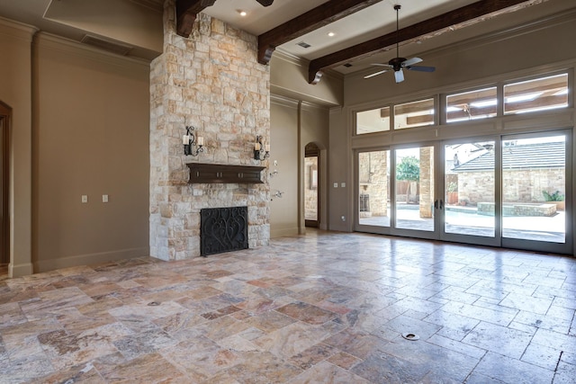 unfurnished living room featuring stone tile flooring, baseboards, a ceiling fan, and beamed ceiling