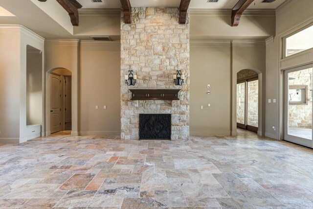 unfurnished living room featuring arched walkways, stone tile flooring, beam ceiling, and baseboards