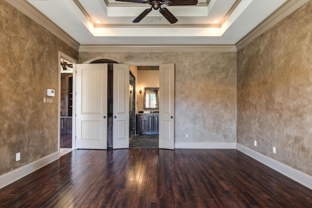 spare room with wood-type flooring, crown molding, ceiling fan, and a raised ceiling