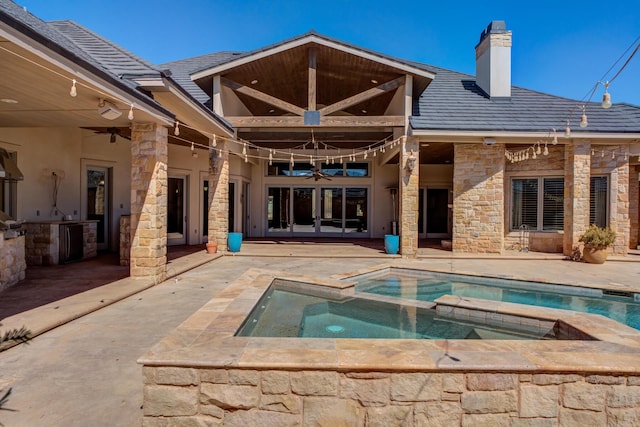 back of house featuring a patio area, stone siding, french doors, an outdoor kitchen, and ceiling fan