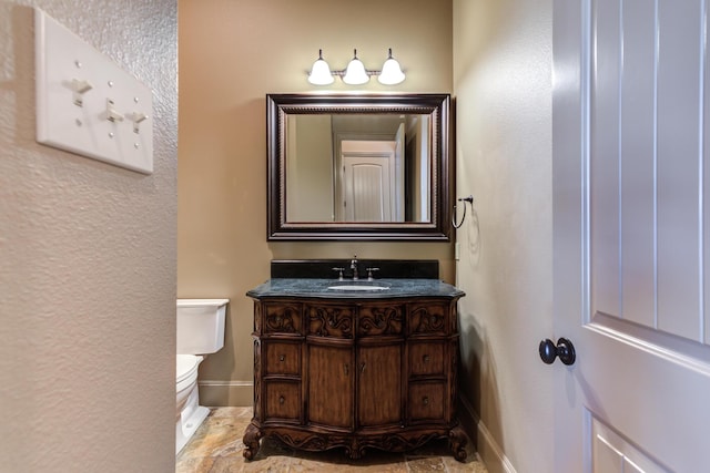 half bathroom with a textured wall, vanity, toilet, and baseboards
