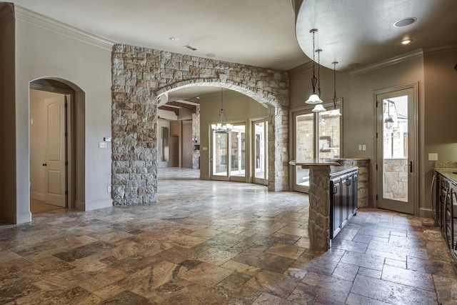 kitchen featuring stone tile flooring, arched walkways, ornamental molding, and hanging light fixtures