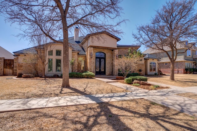 view of front of house featuring french doors, a chimney, and stucco siding