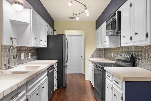 kitchen with sink, dark wood-type flooring, stainless steel appliances, white cabinets, and tile countertops