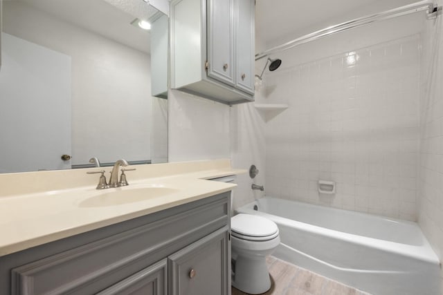 full bathroom with tiled shower / bath, wood-type flooring, vanity, and toilet