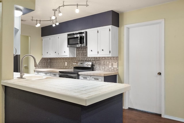 kitchen with sink, white cabinetry, tile countertops, kitchen peninsula, and stainless steel appliances