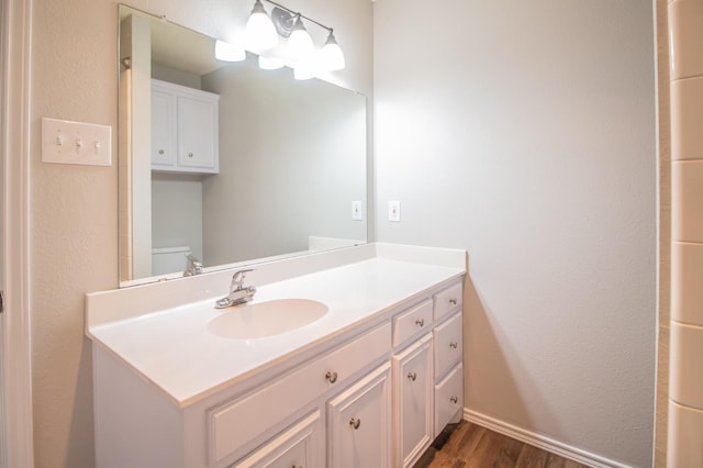 bathroom with hardwood / wood-style flooring, vanity, and toilet