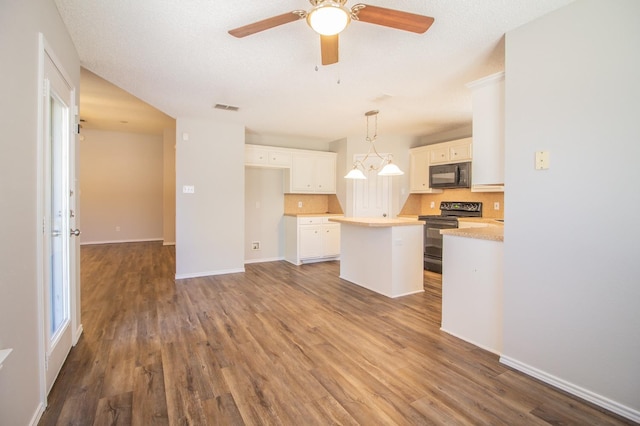 kitchen with wood-type flooring, black appliances, a center island, pendant lighting, and white cabinets