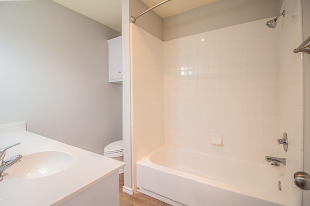 full bathroom featuring tiled shower / bath combo, vanity, hardwood / wood-style flooring, and toilet