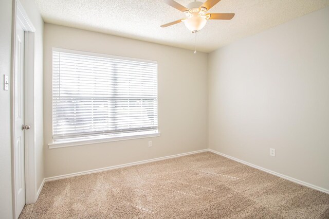 carpeted empty room featuring ceiling fan and a textured ceiling