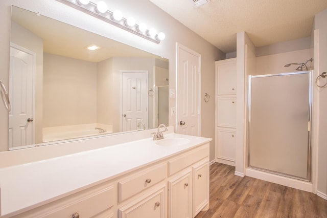 bathroom with vanity, a shower with shower door, hardwood / wood-style floors, and a textured ceiling