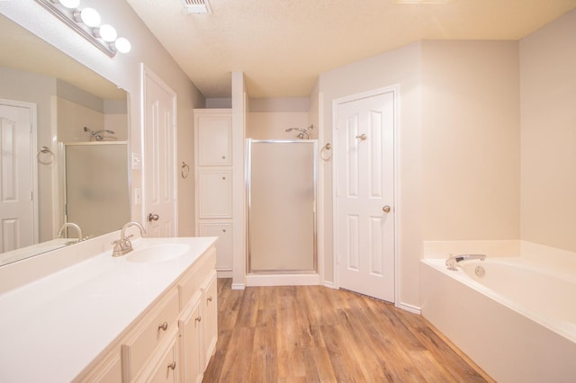 bathroom with vanity, wood-type flooring, independent shower and bath, and a textured ceiling