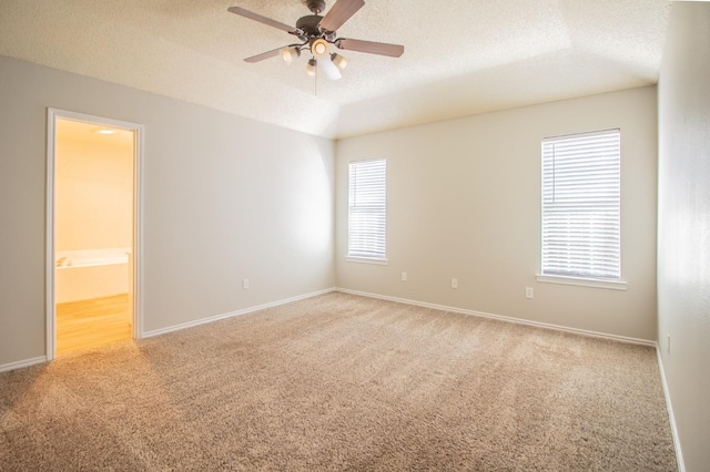 empty room with ceiling fan, light carpet, and a textured ceiling