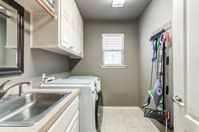 washroom with light tile patterned flooring, cabinets, washer and clothes dryer, and sink