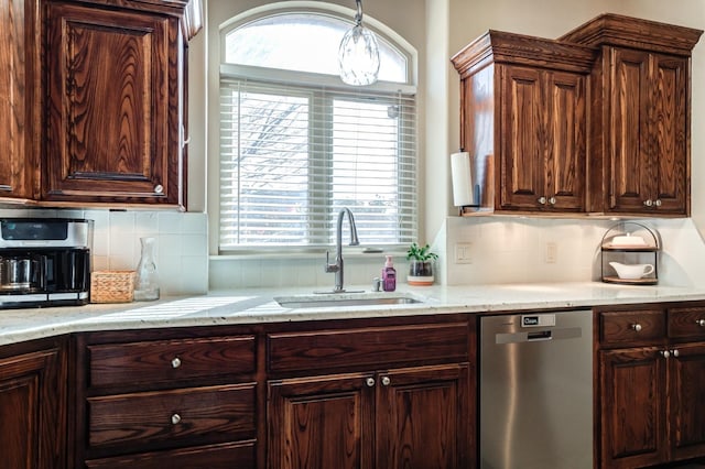 kitchen featuring dark brown cabinetry, sink, tasteful backsplash, light stone counters, and stainless steel dishwasher