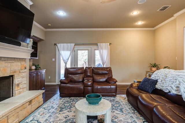 living room featuring a fireplace, crown molding, dark wood-type flooring, and french doors